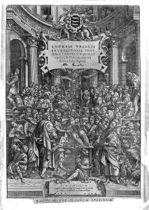 Frontispiece from 1555 edition. Man dissects a woman's abdomen surrounded by many onlookers crowding around, climbing on the structures of the building to watch