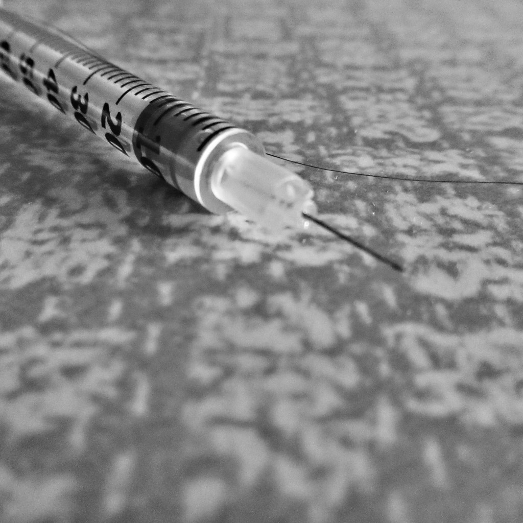 Close up of a syringe on a Formica top in black and white