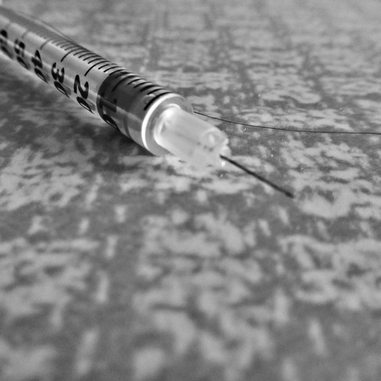 Close up of a syringe on a Formica top in black and white